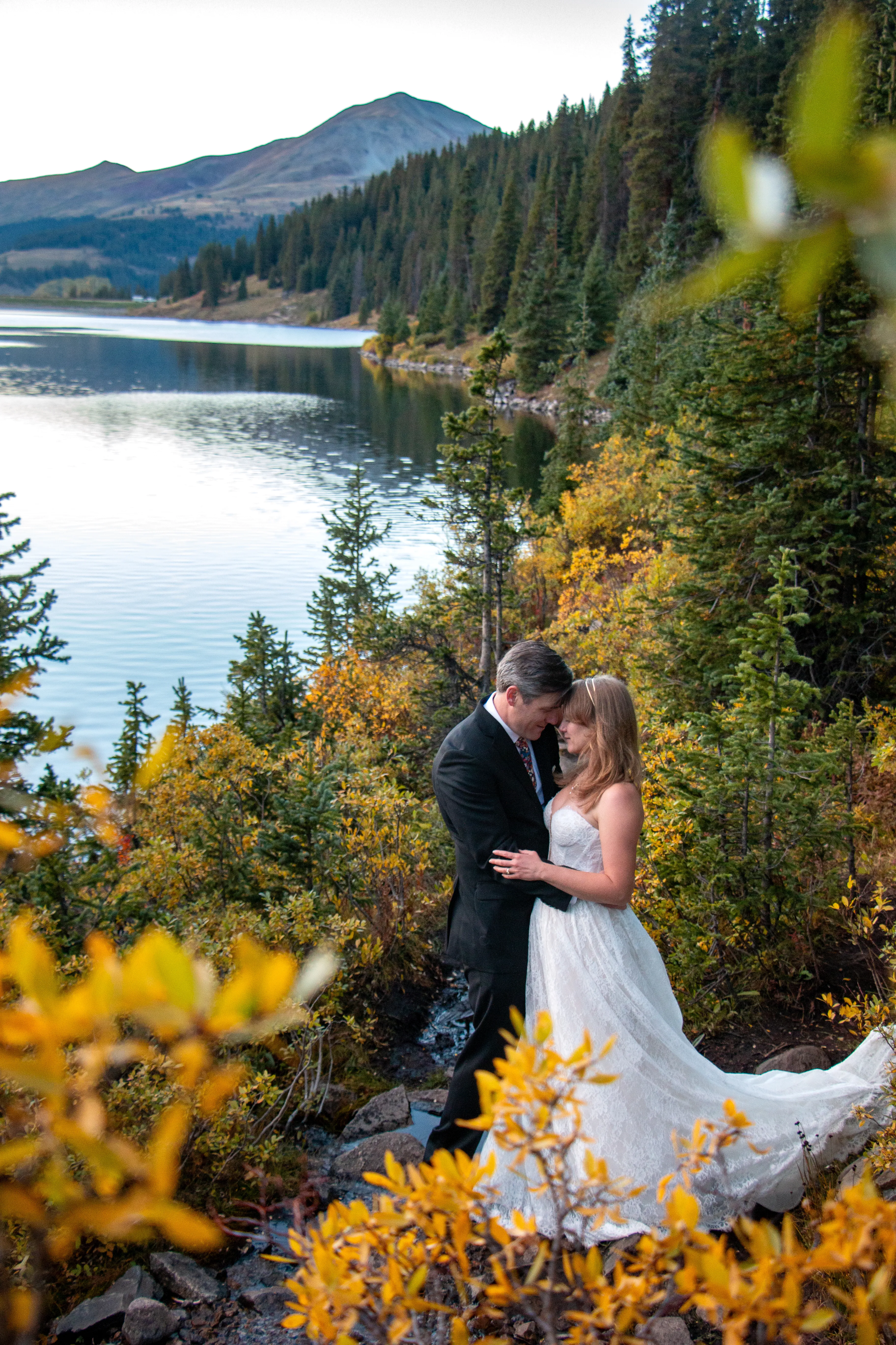 Bride and groom embracing above a mountain lake in autumn